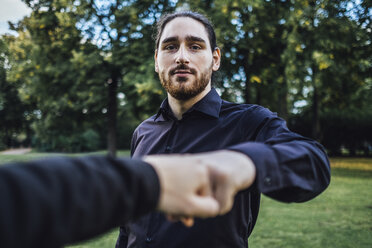 Young businessman greeting business partner in a park, negotiating business transactions - JSCF00108