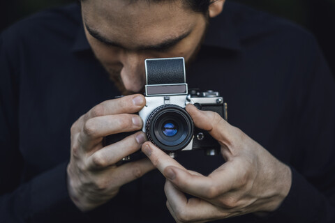 Junger Mann beim Fotografieren mit analoger Kamera, lizenzfreies Stockfoto