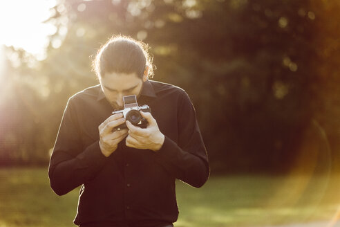 Junger Mann beim Fotografieren mit analoger Kamera - JSCF00112