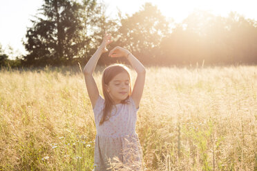 Young girl standing in field at summer evening - LVF07160