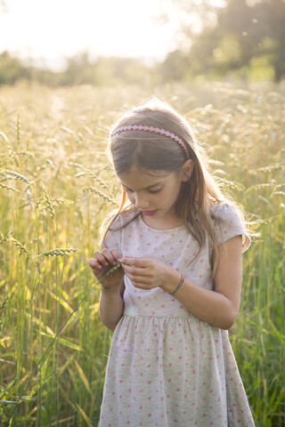 Young girl standing in field at summer evening stock photo