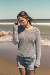 Spanien, junge Frau mit Sonnenbrille am Strand stehend - ACPF00049