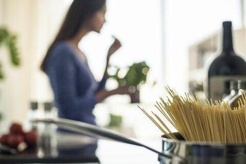 Unscharfes Bild einer jungen Frau, die in der Küche Essen zubereitet, lizenzfreies Stockfoto