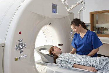 Röntgenassistentin beruhigt Mädchen, das in den CT-Scanner geht - CUF35981