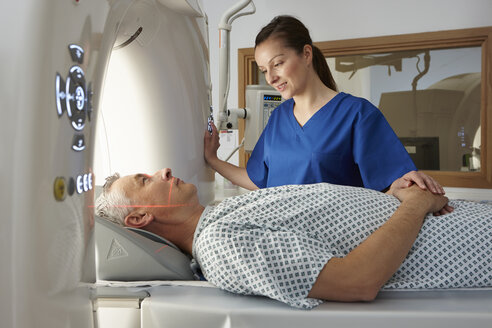 Röntgenassistentin beruhigt Mann, der in den CT-Scanner geht - CUF35984