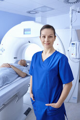 Ein Röntgenassistent steht vor einem Mann, der in ein CT-Gerät geht - CUF35988