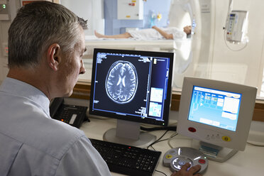 Radiologist looking at brain scan image on computer screen - CUF35996