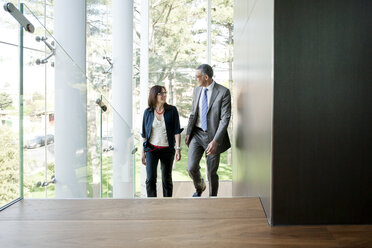 Businessman and woman walking up stairs - CUF36116