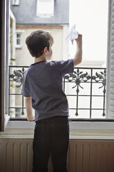 Junge wirft Papierflugzeug aus dem Fenster - CUF36158