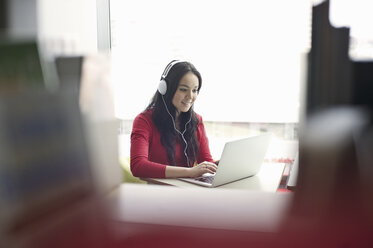 Young woman wearing headphones using laptop - CUF36173