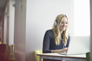 Young woman wearing headphones using laptop - CUF36174