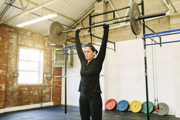 Woman lifting barbell in gym - CUF36180