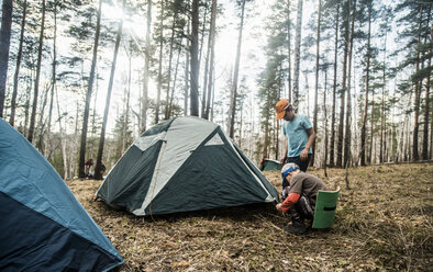 Two boys preparing tent for forest camping - CUF36227