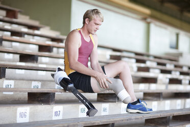 Sprinter preparing, putting on prosthetic leg - CUF36248