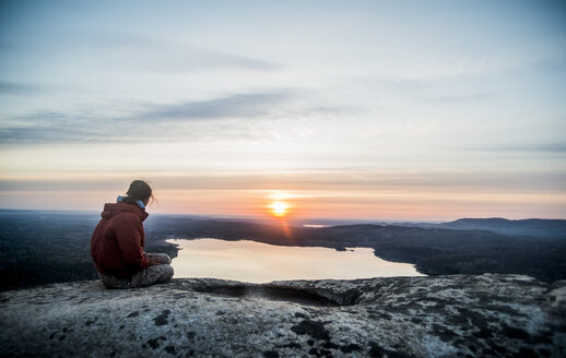 Junge Wanderin mit Blick auf den Sonnenuntergang über einem entfernten See - CUF36262