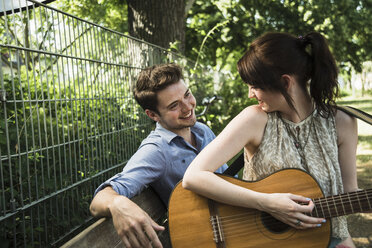 Junges Paar spielt Akustikgitarre im Park - CUF36276