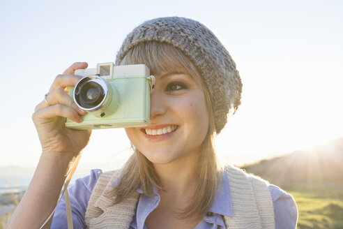 Junge Frau beim Fotografieren mit Kamera bei Sonnenuntergang - CUF36298