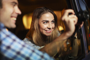 Couple photographing out of city taxi window at night - CUF36315