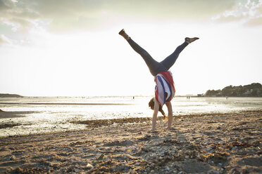 Junge Frau im Handstand am Strand von Bournemouth, Dorset, UK - CUF36347