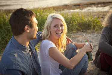 Drei erwachsene Freunde trinken Bier am Strand von Bournemouth, Dorset, Großbritannien - CUF36351