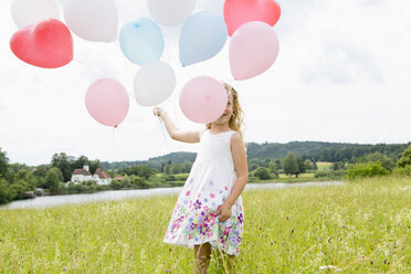 Girl holding balloons in field - CUF36405