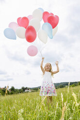 Girl holding balloons in field - CUF36406