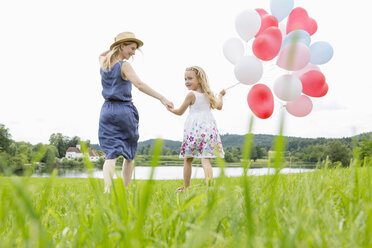 Mutter und Tochter im Feld mit Luftballons - CUF36408