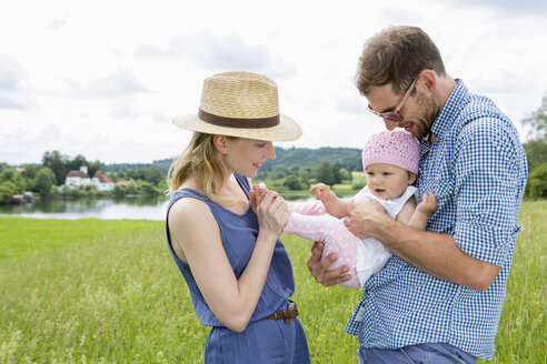 Eltern halten ihre kleine Tochter auf einem Feld - CUF36416