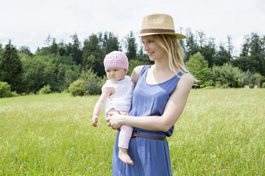 Mutter hält ihre kleine Tochter auf einem Feld - CUF36428