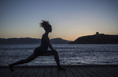 Junge Frau beim Yoga am Meer, Silhouette - CUF36452