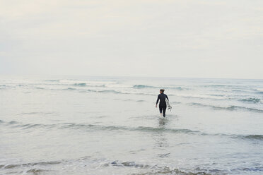 Surfer with surfboard walking into ocean, Lacanau, France - CUF36500