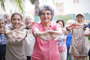 Medium group of seniors exercising in retirement villa garden - CUF36608