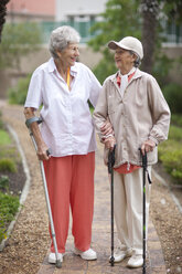 Two senior women strolling in retirement villa garden - CUF36611