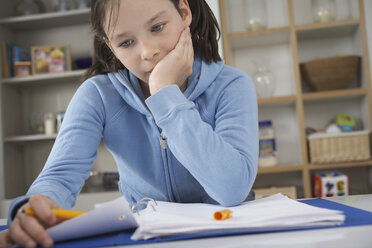 Girl sitting at kitchen counter struggling with homework - CUF36651