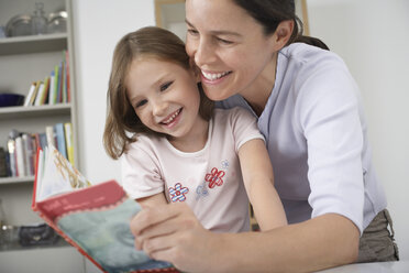 Mother and young daughter reading storybook - CUF36653