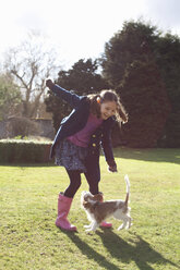 Mädchen spielt im Garten mit ihrem Hund - CUF36658