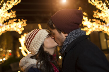 Young couple kissing on street at christmas - ISF14442