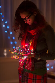 Junge Frau hält ein Knäuel von Weihnachtslichtern - ISF14448