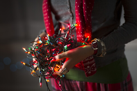 Nahaufnahme einer jungen Frau, die ein Knäuel von Weihnachtslichtern hält, lizenzfreies Stockfoto