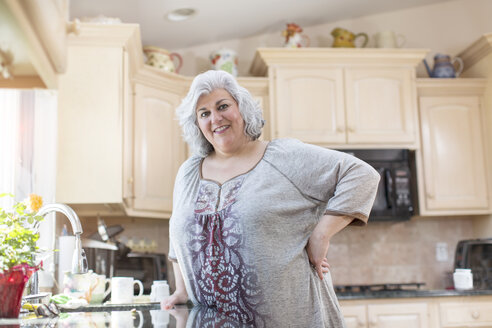 Porträt einer reifen Frau mit Hand auf der Hüfte in der Küche - ISF14490