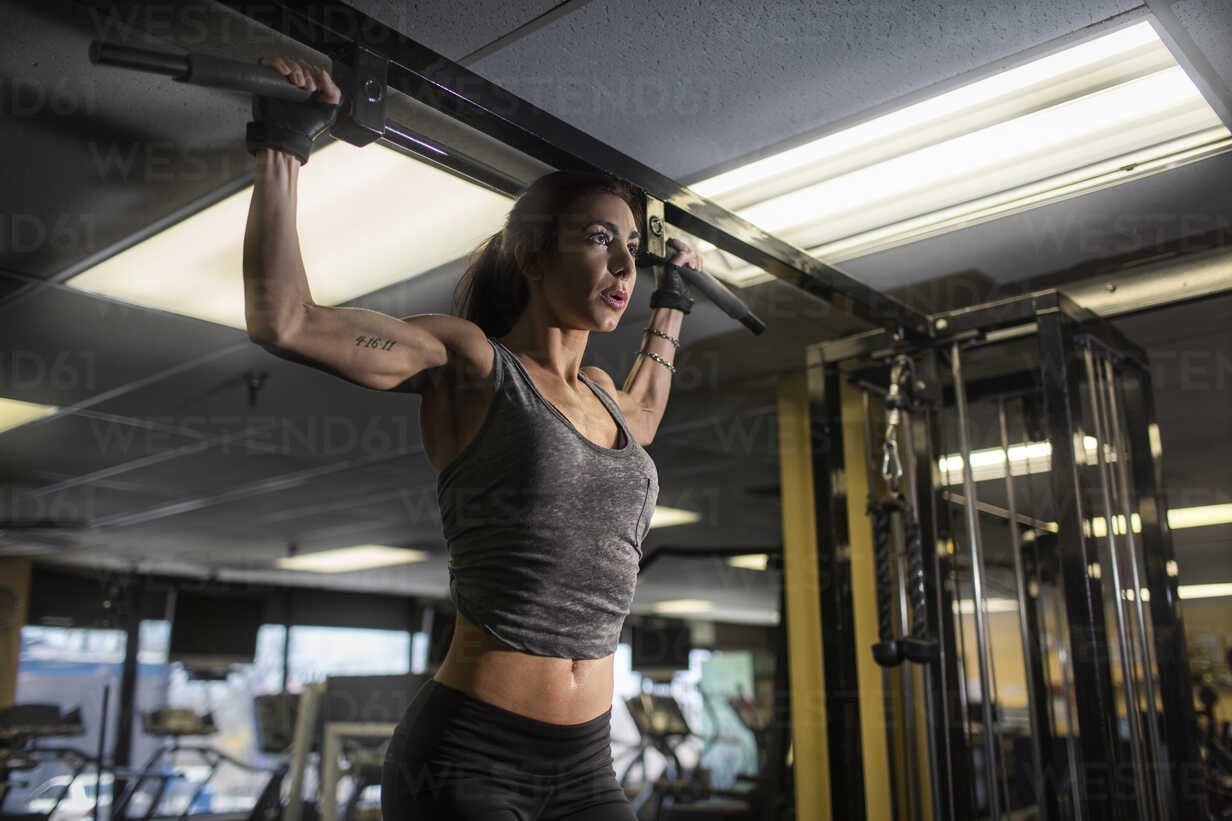 Mid adult woman doing pectoral exercise in gym stock photo