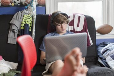 Jugendlicher auf einem Stuhl sitzend mit einem Laptop-Computer - ISF14527
