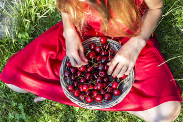 Girl with basket of cherries sitting on a meadow, partial view - SARF03813