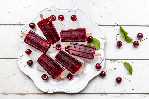 Homemade cherry ice lollies, ice cubes and cherries on plate stock photo