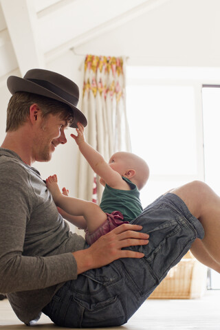 Vater mit Hut und Baby auf dem Schoß, lizenzfreies Stockfoto