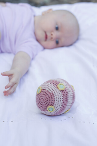 Babymädchen greift nach dem Ball, lizenzfreies Stockfoto