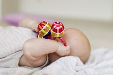 Baby girl lying with rattle covering face - CUF36781