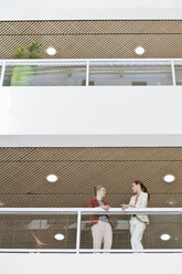 Two female work colleagues taking a break on office balcony - CUF36822