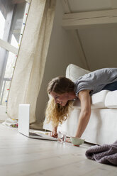 Frau auf dem Sofa liegend mit Laptop - CUF36869