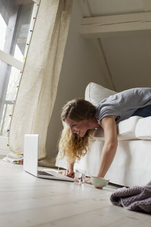 Woman lying on sofa using laptop - CUF36869